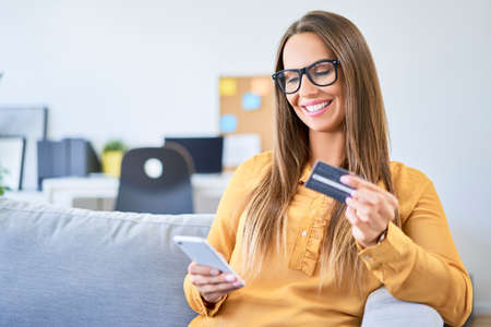 Young woman using credit card and smartphone to pay for shopping onlineの写真素材
