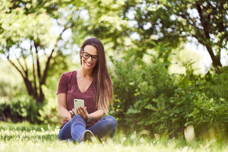 Young woman making phone call to insurance agent while inspecting scratched carの写真素材