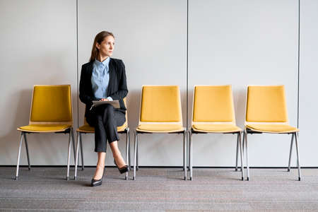 Young woman using phone and having coffee while on break. Office worker sitting on floorの写真素材