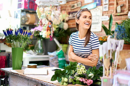 Young florist cutting flower for bouquet at the counter of her shopの写真素材
