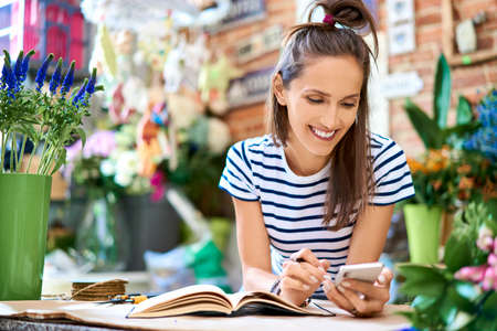 Florist selecting flowers for bouquet and arranging them together at the counter topの写真素材