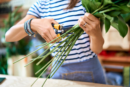 Florist selecting flowers for bouquet and arranging them together at the counter topの写真素材