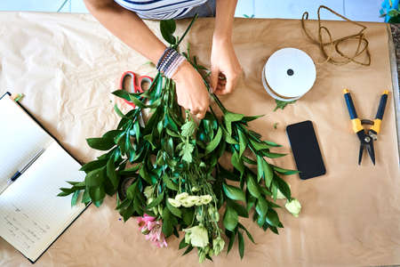 Florist selecting flowers for bouquet and arranging them together at the counter topの写真素材