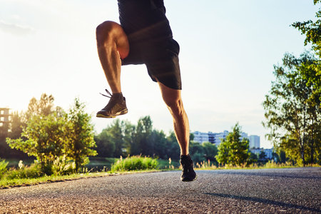 Legs of muscular man jogging. Working out during evening in the cityの写真素材