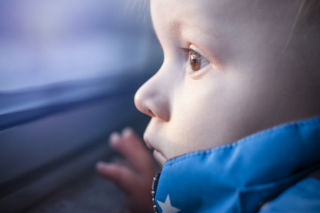 Big eyes of baby toddler. Close up baby face looking in windowの写真素材