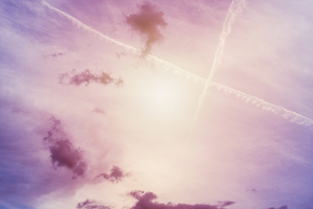 Purple and pink sky in sunset with cross of traces of aircrafts backroundの写真素材