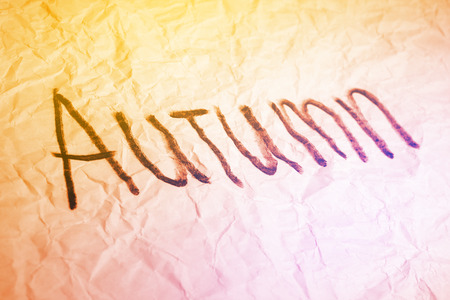 Autumn word hand made on crumpled paper texture colorful toned in yellow and pink background.の写真素材