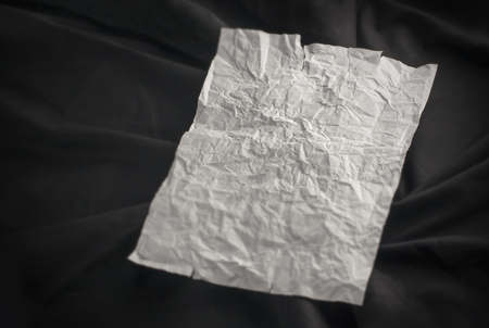 Battered white paper texture on black background. Crumpled shabby piece of paperの写真素材