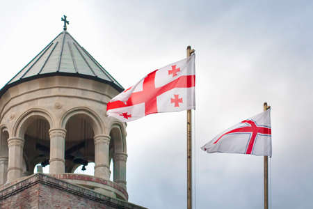 Georgia flags with ancient georgian church and sky in background. Travel to caucasian country