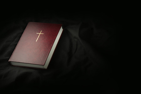 Bible on dark textile background. Holy Scripture with cross with copy spaceの写真素材