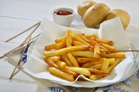 french fries and ketchup on a white wooden tableの写真素材