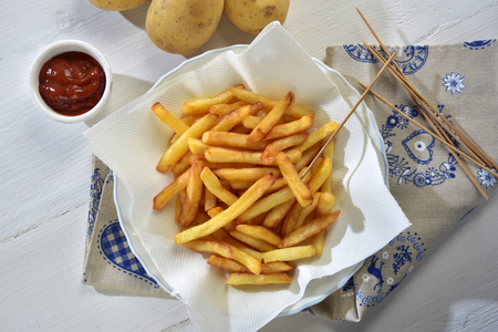 french fries and ketchup on a white wooden tableの写真素材