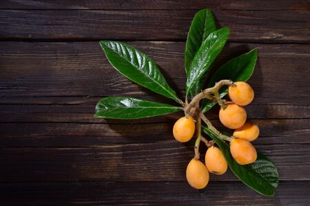 Nespole with branch and leaves on a wooden tableの写真素材