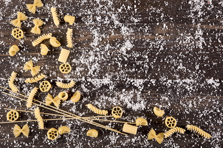 Raw raw Italian pasta on a wooden table with saltの写真素材