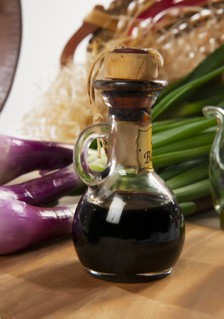 Balsamic vinegar and spring onions on a wooden cutting boardの写真素材