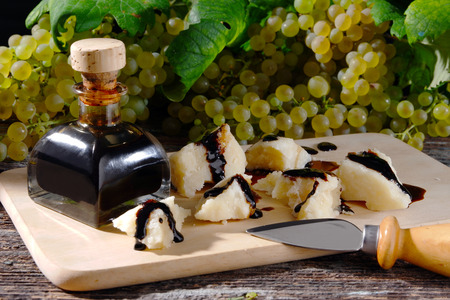 Balsamic vinegar of Modena with pieces of Parmesan cheese and grapes in the backgroundの写真素材