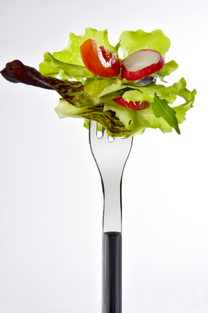 bite of mixed salad on fork with white backgroundの写真素材