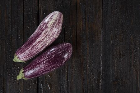 wet purple eggplant on a dark wooden table
