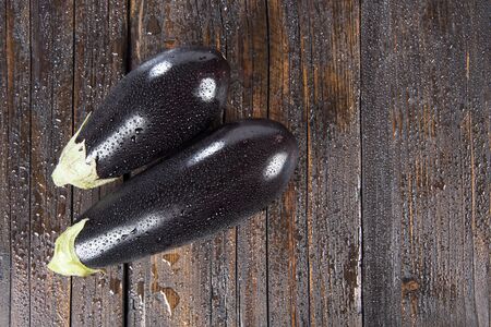 wet purple eggplant on a dark wooden tableの写真素材