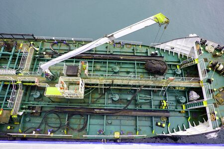 worker operating a crane on a ship and the port