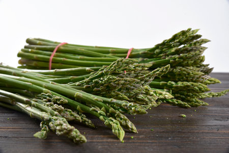 Fresh wild asparagus arranged on a wooden table and white backgroundの写真素材