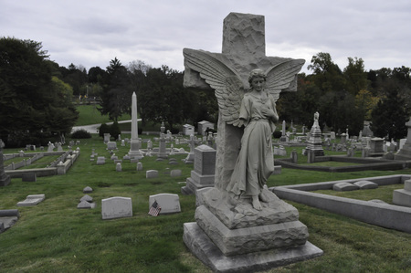 Statue of an Angel Looking Down Upon a Grave in a Cemetery