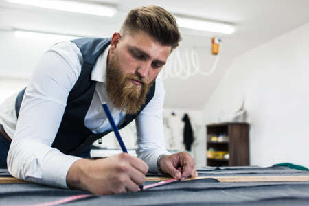 Young bearded tailor working on new clothing designの写真素材