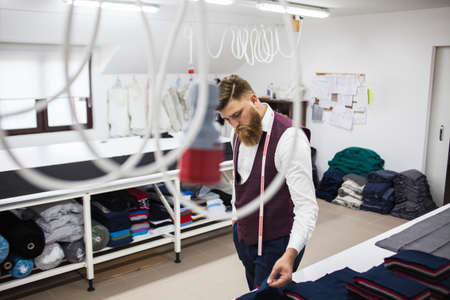 Young bearded tailor working on new cloting designの写真素材