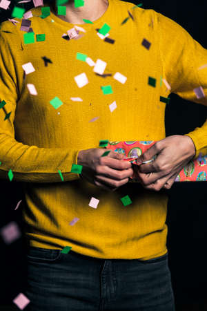 Young man i yellow sweater open present for partyの写真素材