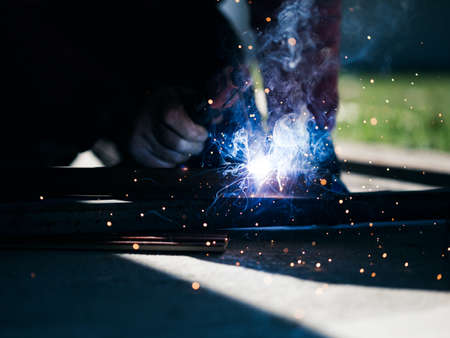 Welder working on sunny day in shade