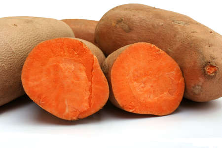 Two halves of a cut sweet potato in front of whole sweet potatoesの写真素材