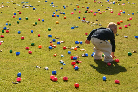 Little Boy bending down to collect an egg in an Easter egg hunt.の写真素材