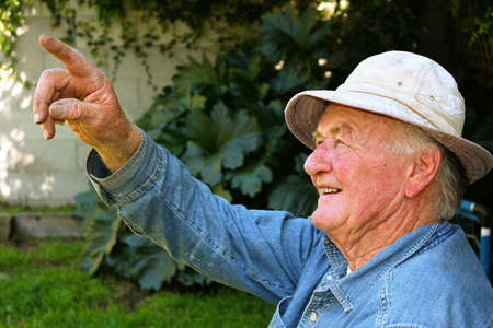 Older man pointing to something in his backyardの写真素材
