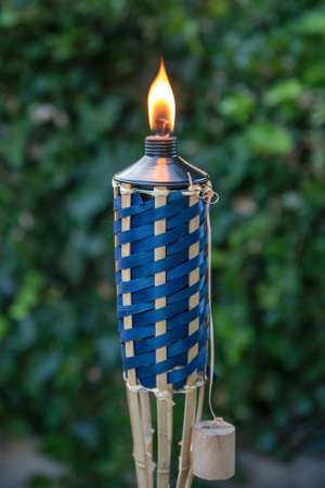 Close up of lit Tiki torch at dusk before a backyard party.の写真素材