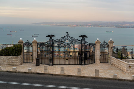 Beautiful black ornate gates at the top of the Bahai Gardens in Carmel above Haifa, Israel. View of the Haifa bay and ships.の写真素材