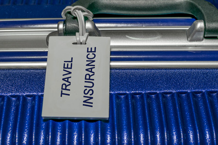 Travel insurance luggage tag tied to a suitcaseの写真素材