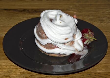Close up shot of sweet desert with chocolate ice cream, whipped cream and strawberry on black plateの写真素材