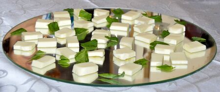 Cubed mozzarella cheese with basil on mirror platterの写真素材