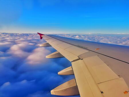 Wing of airplane reflecting sunset over the cloudsの写真素材