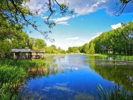 Small cabin near beautiful lake that reflects the blue sky, beautiful landscape near Craiova, Romaniaの写真素材