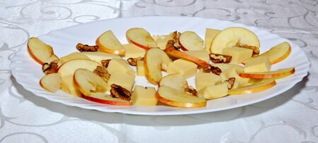 Fresh platter with mix of cheddar cheese bits, apple slices and wall nuts prepared and arranged on white plate for a tasting, cheese tasting platter with fruit and nutsの写真素材