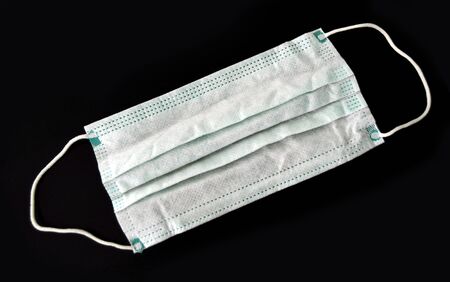 Medical face mask, closeup of a surgical mask on a dark background, virus protection during pandemicの写真素材