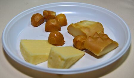 Assortment of Polish cheese on a white plate: Tilsit or TylÅ¼ycki, GoÅka or Gouka and Oscypek cheeses sliced and ready for a cheese tasting. Smokey cheeses from Poland platingの写真素材