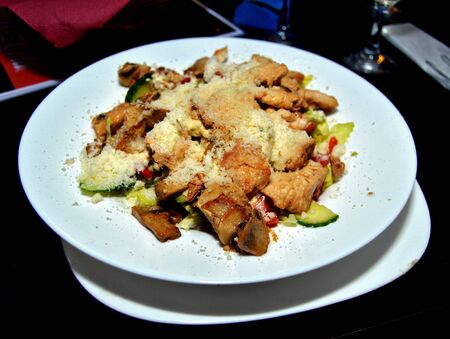 Serving of healthy salad with vegetables, chicken bits and sprinkled with parmesan cheese, a delicious dish great for diets made with organic ingredientsの写真素材