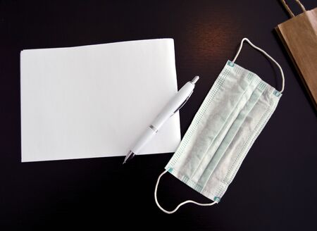 World Health pandemic scare, face mask on desck next to paper notepad and pen great for headlineの写真素材
