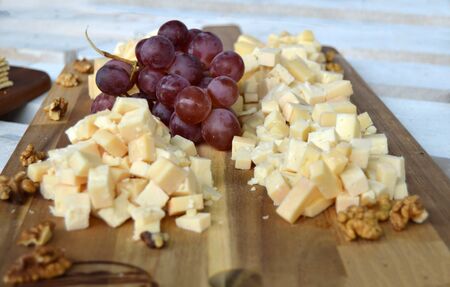 A platter full of delicious food made for a cheese tasting, containing small bits of hard cheeses, a red grape and some wall nuts, natural and organic, perfect snackの写真素材