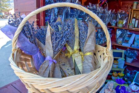 A wicker basket with dry purple lavender flowers wrapped in old newspapers, a bouquet of dried lavenders sold as an aromatic souvenir in a shopの写真素材