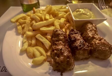 Close-up of romanian meal consisting of skinless sausages made from mixed meats called "mici" which are grilled, served next to fries and the traditional mustard, a go-to deicacy in Romaniaの写真素材