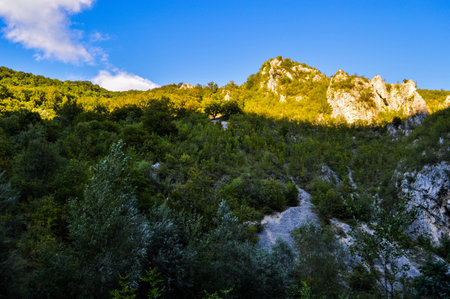 Sun shining over green forest and Rocky eroded terrain, Sohodol Gorges(Cheile Sohodolului), Valcan mountains, in Gorj county, Romaniaの写真素材