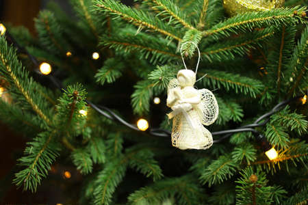 Christmas angel on christmas tree branch, lights hanging in a treeの写真素材